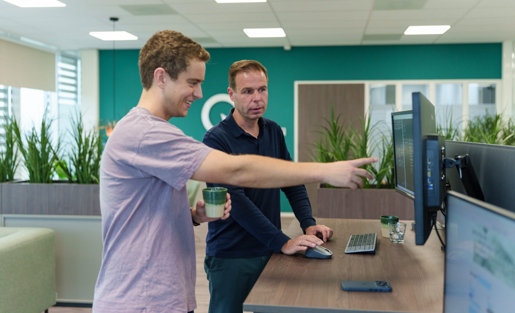 Twee collega's overleggen bij een scherm