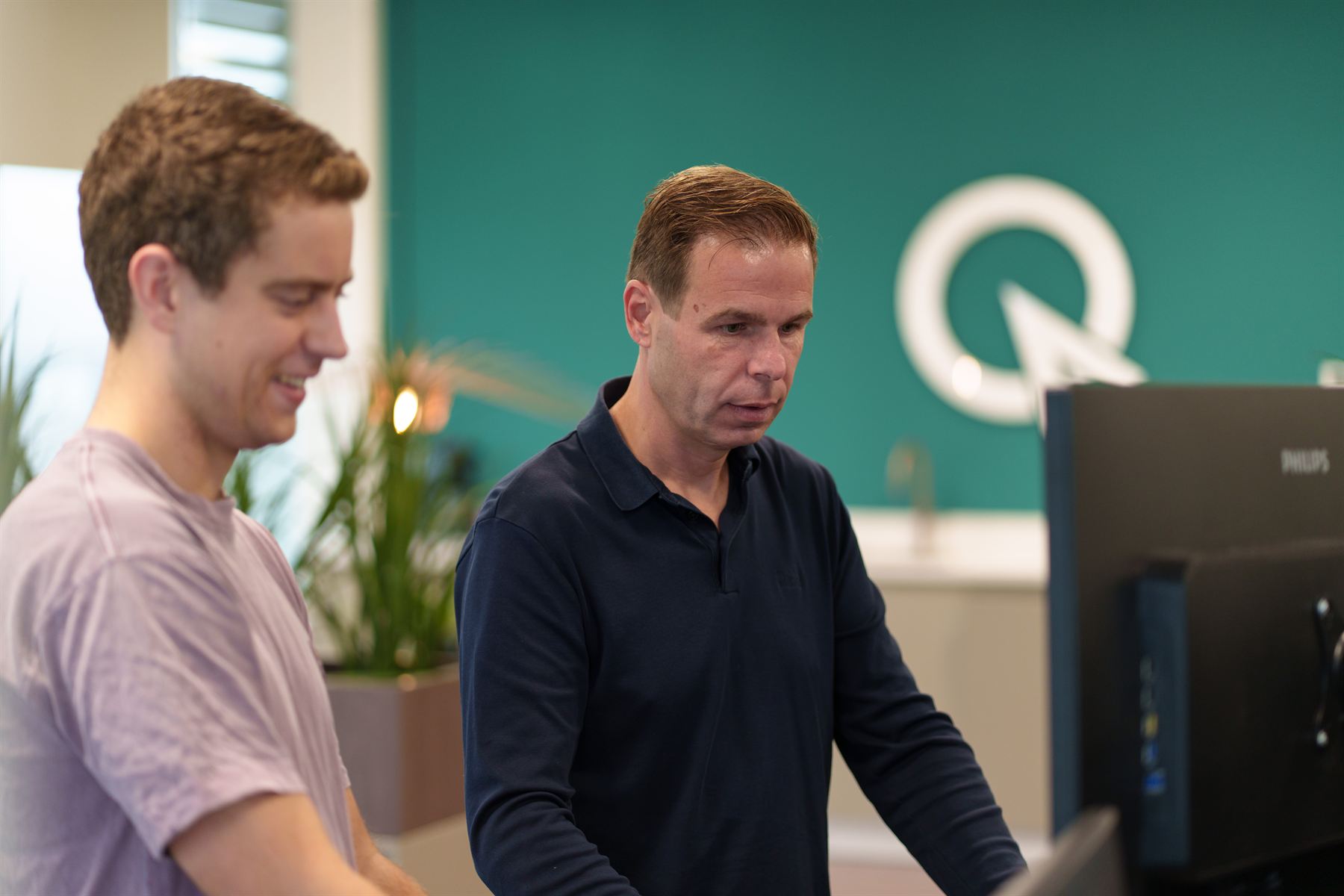 Twee researchers overleggen samen aan een scherm voor de logowand van Quant Atelier